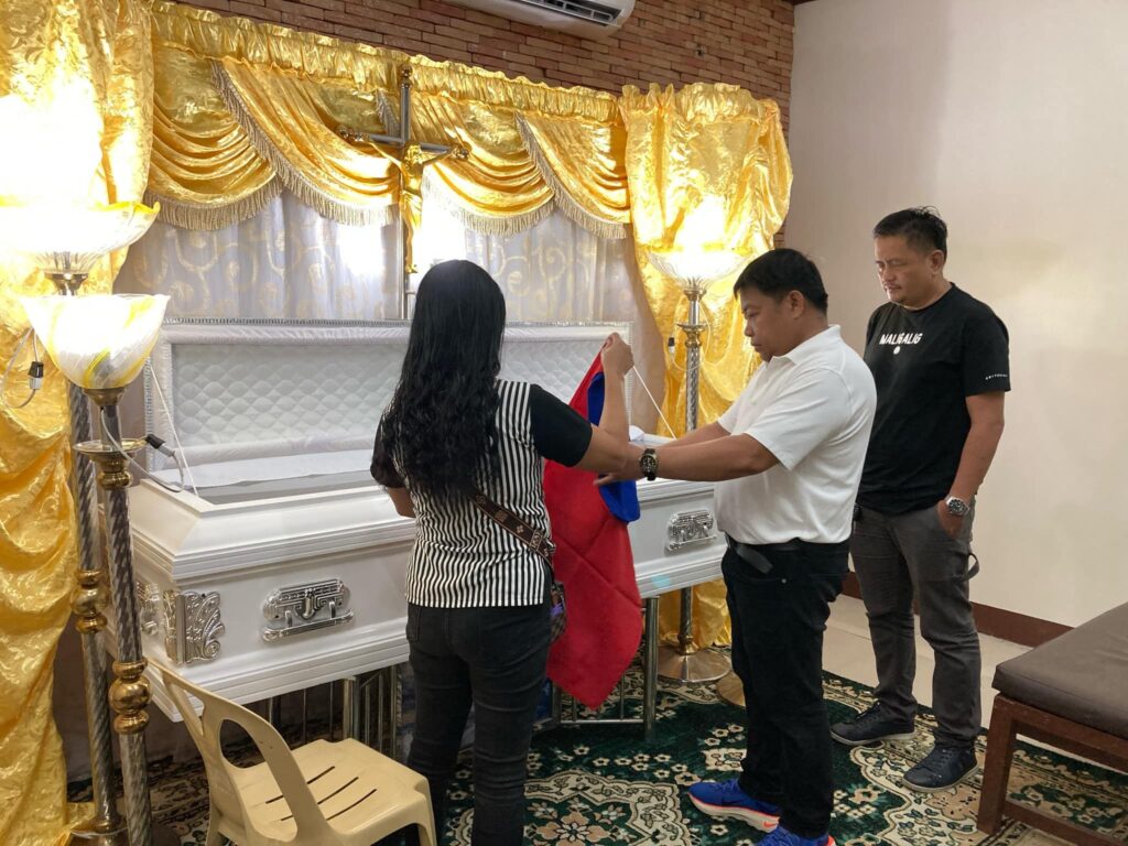 Officials of Barangay Pachoca prepare to drape the Philippine flag over the coffin to honor their late former leader.